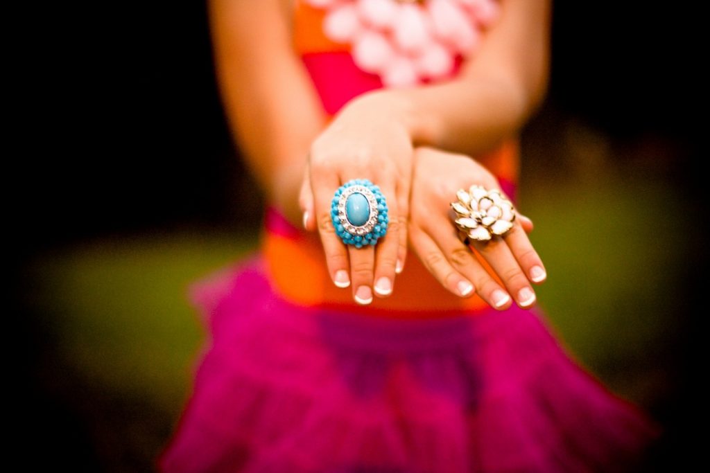 dame in roze kleding met handen vooruit met twee grote ringen