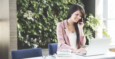 dame aan bureau met telefoon in handen