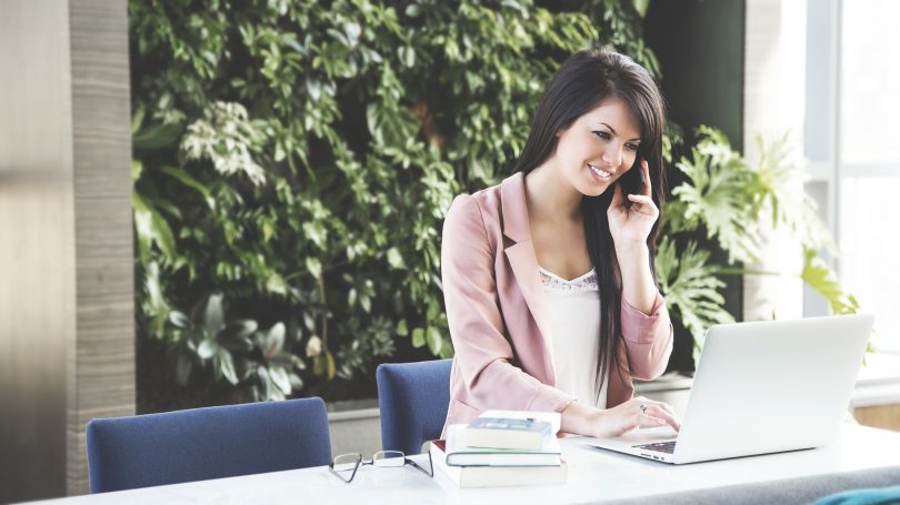 dame aan bureau met telefoon in handen