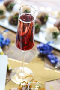 gouden ster met daarop glas roze alcohol en hapjes op de achtergrond