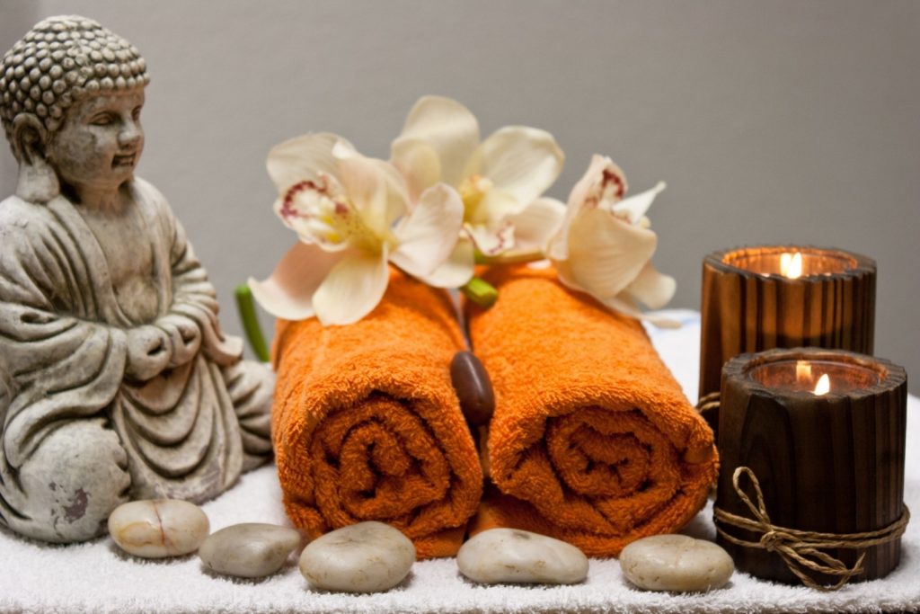boedha, oranje handdoeken, bruine kaarsen, stenen en orchidee