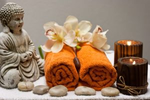 boedha, oranje handdoeken, bruine kaarsen, stenen en orchidee