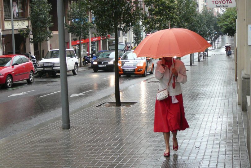 dame in rode rok met paraplu in regen in barcelona