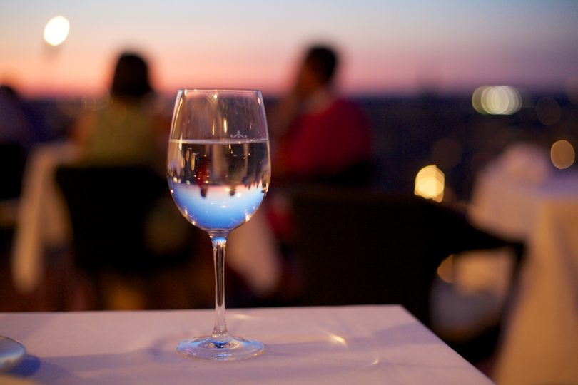 glas wijn op tafeltje in restaurant met ondergaande zon