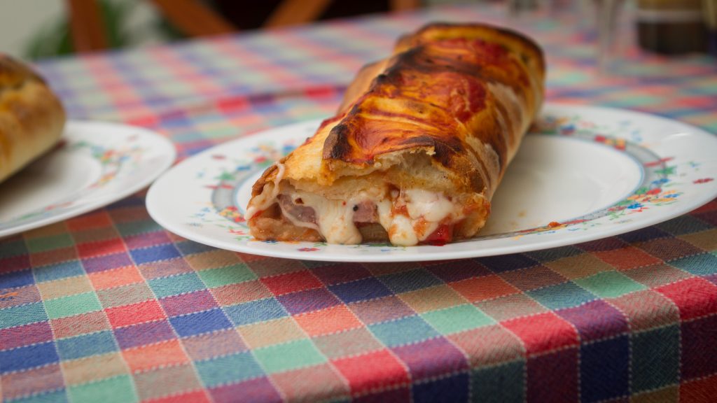 pizza calzone op een bord met geblokt tafelkleed op tafel