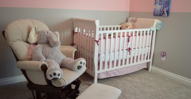 babykamer met bed stoel roze behang