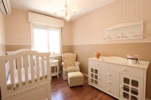 beige en roze babykamer met ledikant commode stoel