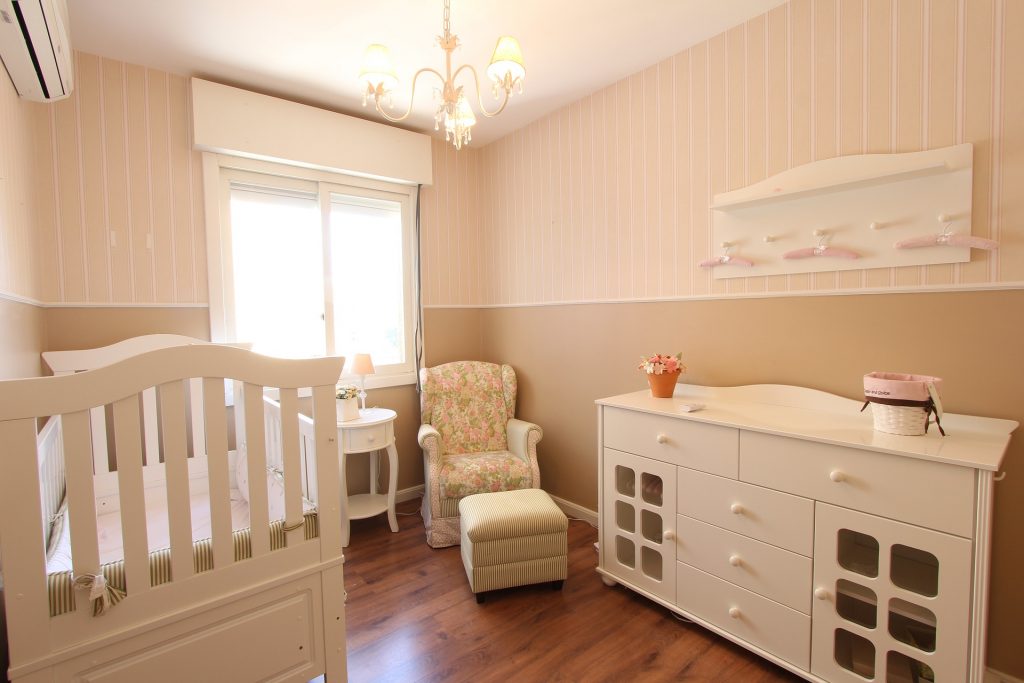 beige en roze babykamer met ledikant commode stoel 