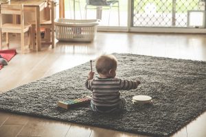 klein kind op vloerkleed met trommel