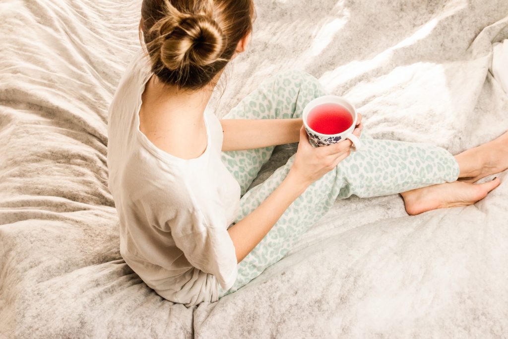 vrouw in pyjama op bed met kop thee
