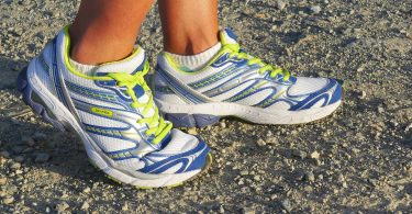 hardloopschoenen met gele veters in zand