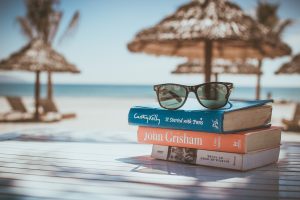 stapeltje leesboeken met zonnebril op strand