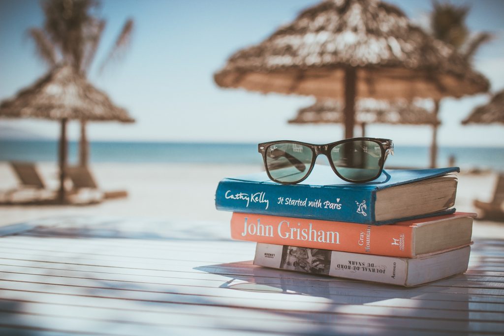 stapeltje leesboeken met zonnebril op strand