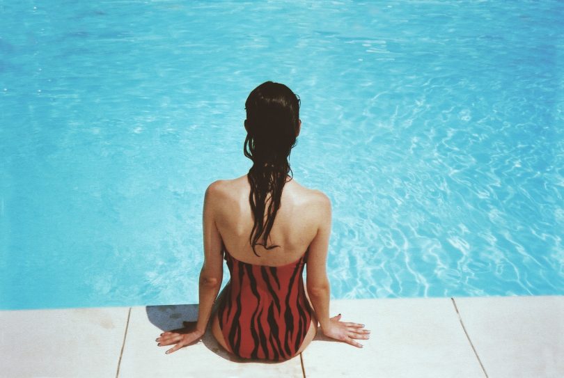 vrouw zit aan rand zwembad
