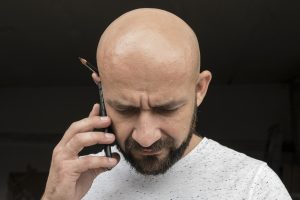 kale man met baard aan telefoon