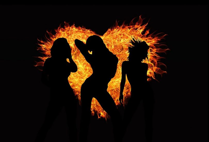 3 vrouwensilhouetten tegen zwarte achtergrond met hart van vuur